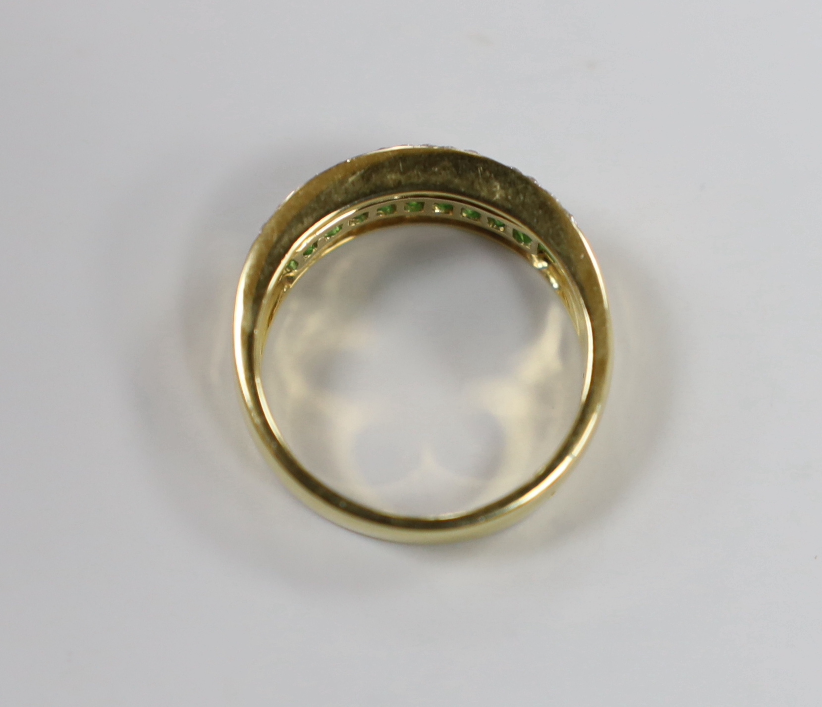 A modern 750 yellow metal, emerald and diamond cluster set triple row ring, size P/Q, gross weight 7.1 grams.